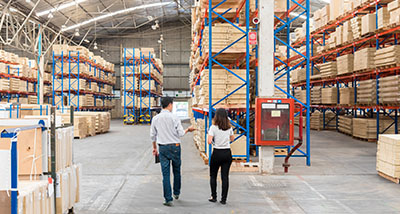 two people walking in a warehouse with wholesale stock in storage
