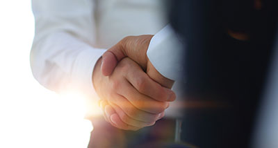 two businesspeople shaking hands with a bright background
