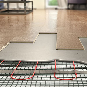 a laminate floor with a section exposing the insulation and red underfloor heating pipes