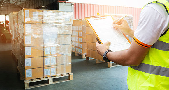 a man with a clipboard writing notes about stock on palettes